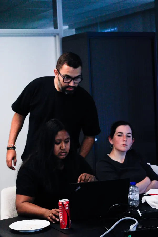 Instructor leaning in over two participants working at a laptop